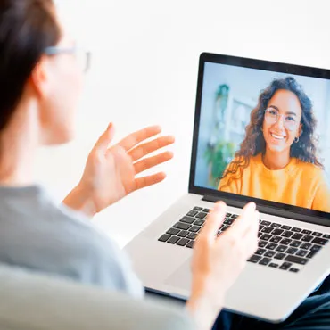 Imagen que muestra a una psicologa utilizando un ordenador para realizar una sesión de terapia en línea a través de videoconferencia.